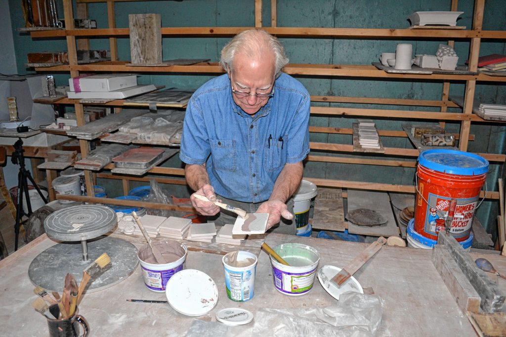 Andy Hampton of Hampton pottery paints tiles, a hands on craft he will offer at his home studio during N.H. Open Doors. TIM GOODWIN / Insider staff
