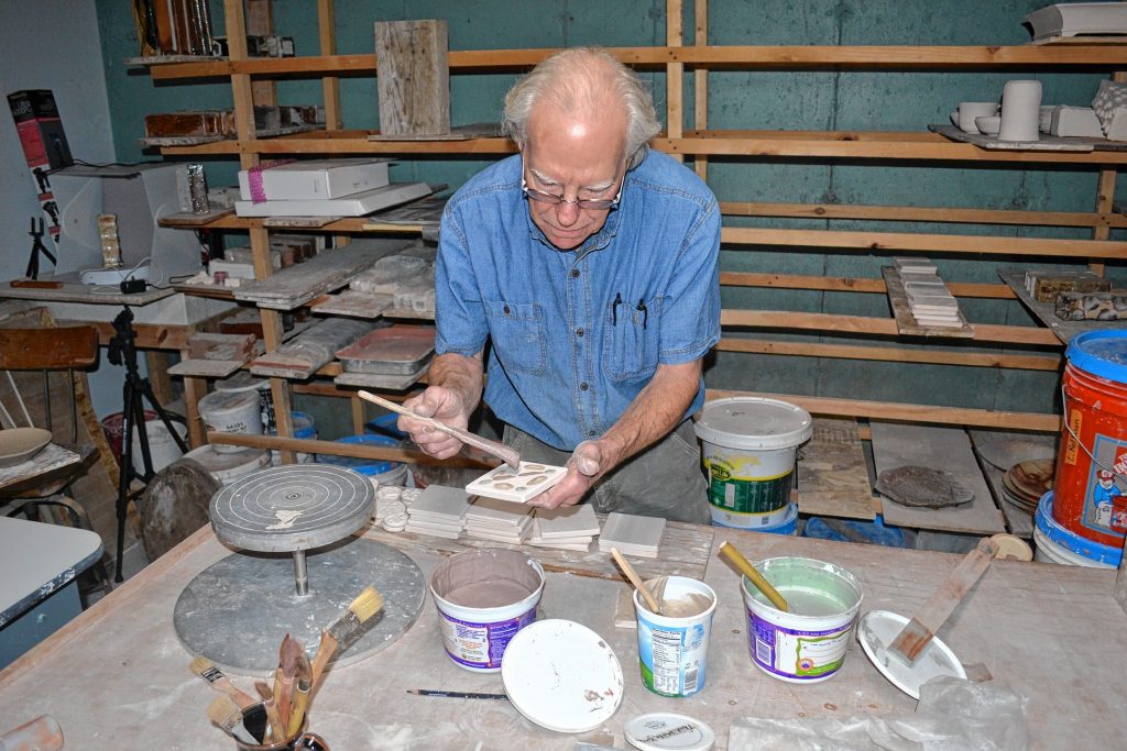 Andy Hampton of Hampton pottery paints tiles, a hands on craft he will offer at his home studio during N.H. Open Doors. TIM GOODWIN / Insider staff