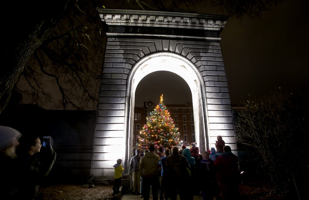 People watch from underneath the State House arch Friday night as the 30th annual Christmas tree lighting capped off a night of festivites. Santa Claus arrived via the Concord fire ladder truck and animal rides around the Park Street to Capitol Street and the evening finished with fireworks over Main Street. GEOFF FORESTER