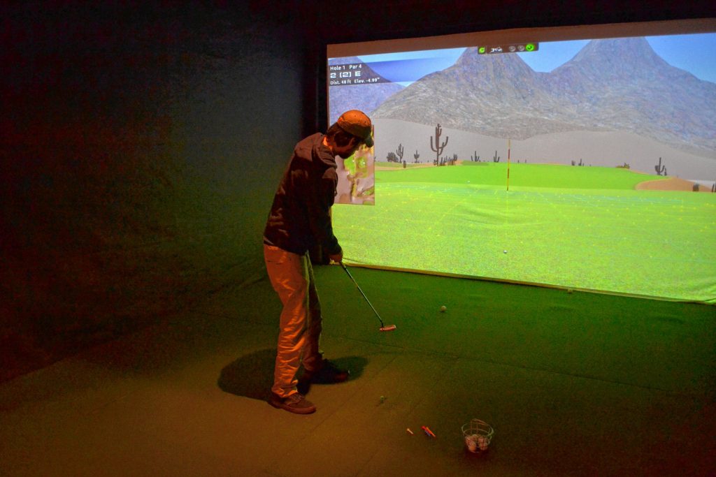 Jon watches as his putt travels toward the hole during a round at Beaver Meado's indoor simulators. TIM GOODWIN / Insider staff