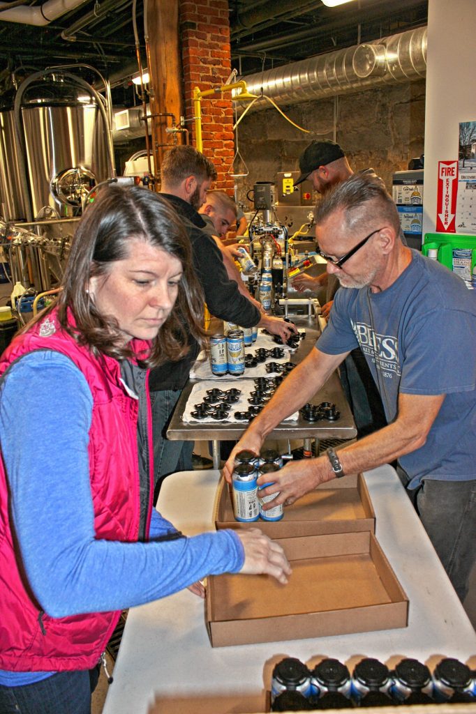 Beth Mayland (left), brewer and co-owner of Concord Craft Brewing Co., and Doug Bogle, Concord Craft's head brewer, man the end of the canning line at the brewery last week. Their task was to manually snap the cans into 4-packs and then box and stack the packs. The final stop will be a store shelf, then, ultimately, your belly. JON BODELL / Insider staff