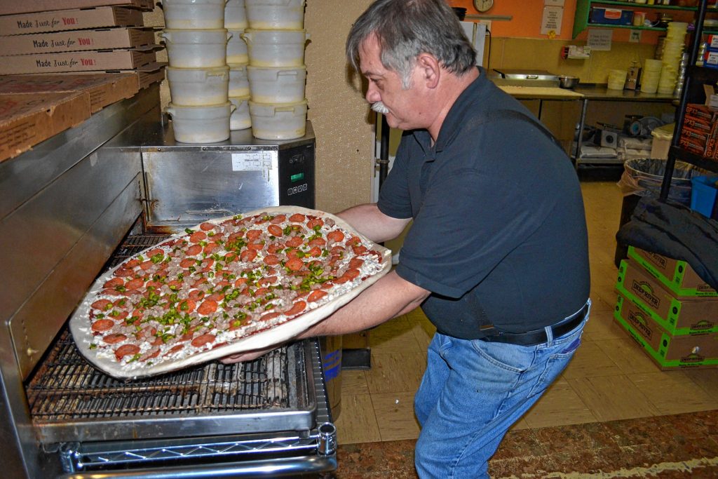 Donatello's owner Bob Boisvert puts a super dominator, loaded with pepperoni, sausage and green pepper, in the oven. TIM GOODWIN / Insider staff