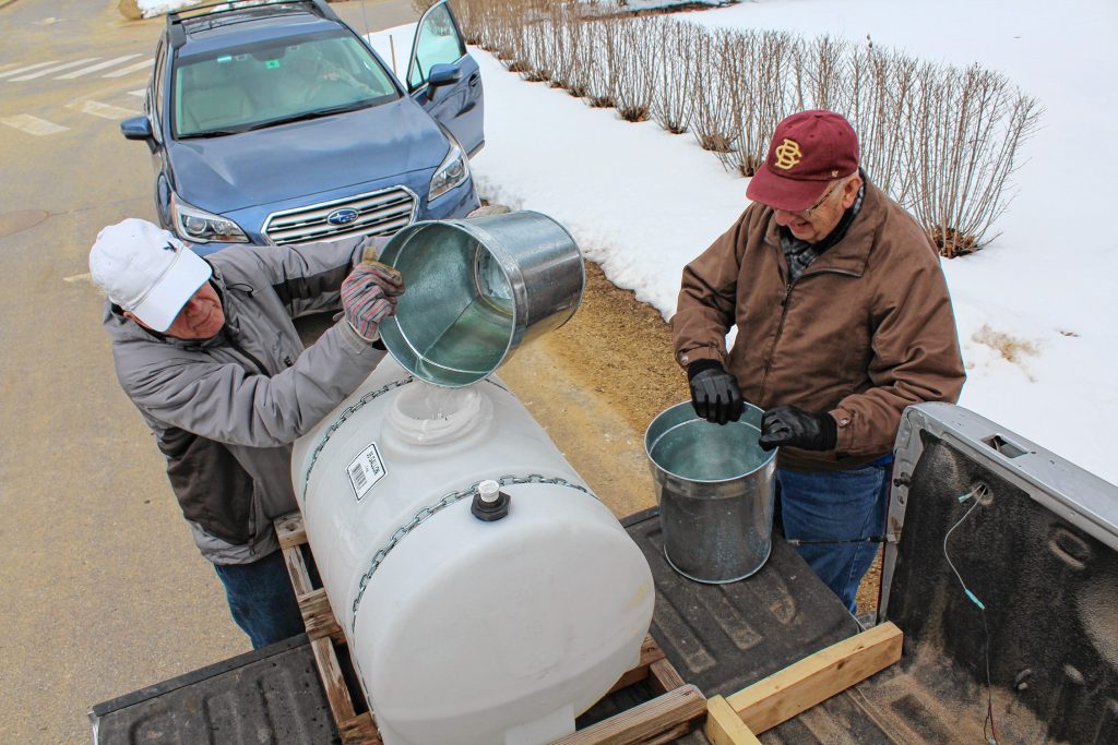 John Sahlin pours his sap into the holding tank, while Leo VanBeaver is next to add more to make maple syrup. Courtesy