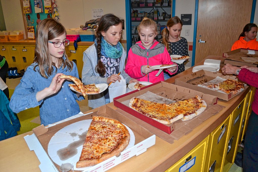 Kenadee Couger and Mahalie Burdette grab slices of pizza from Constantly Pi...
