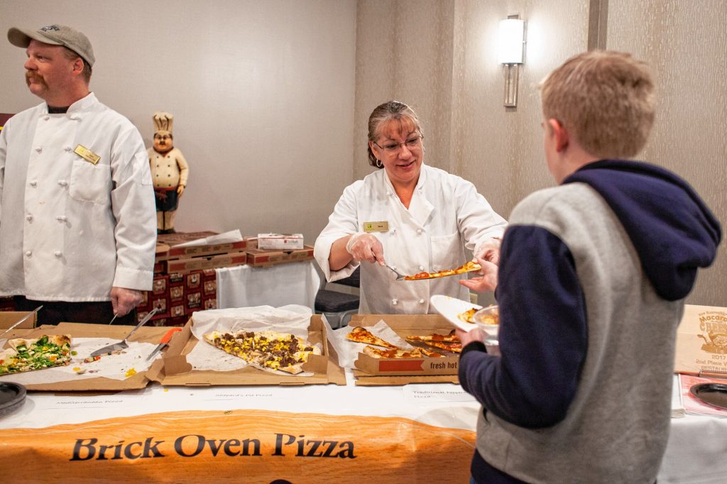Rene Berube serves slices of EJ's on Main pizza during the Pizza Pie Showdown at the Holiday Inn in downtown Concord on Pi Day, Mar. 14, 2018. Proceeds from the event, hosted by the Concord Monitor and Insider, went to support the Friendly Kitchen. (ELIZABETH FRANTZ / Monitor staff) Elizabeth Frantz