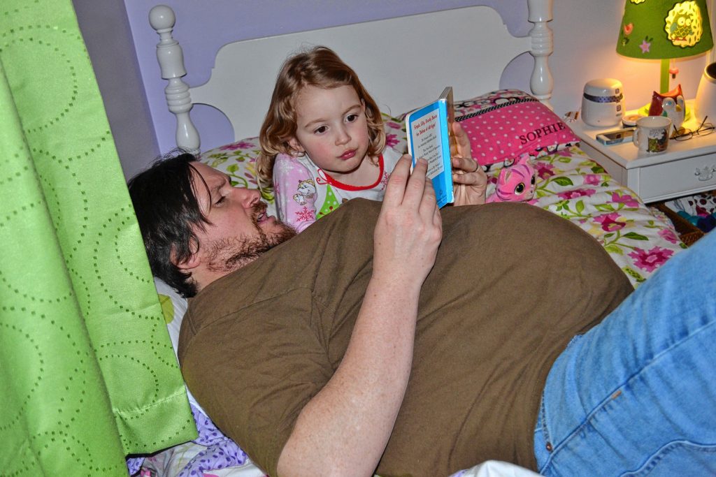Even after a full 13 hours of being fake pregnant, Tim still found the energy to lay around and read stories to his daughter, Sophie. MARY GOODWIN / For the Insider