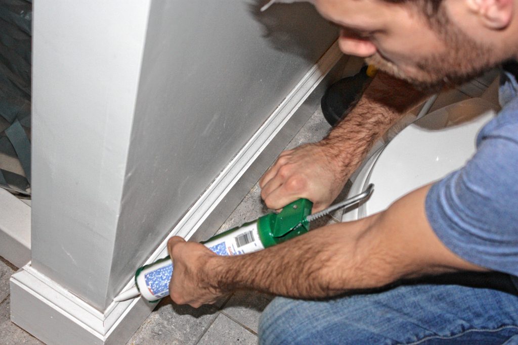 Jon applies some caulking to the baseboard in his bathroom. AIMEE BODELL / For the Insider