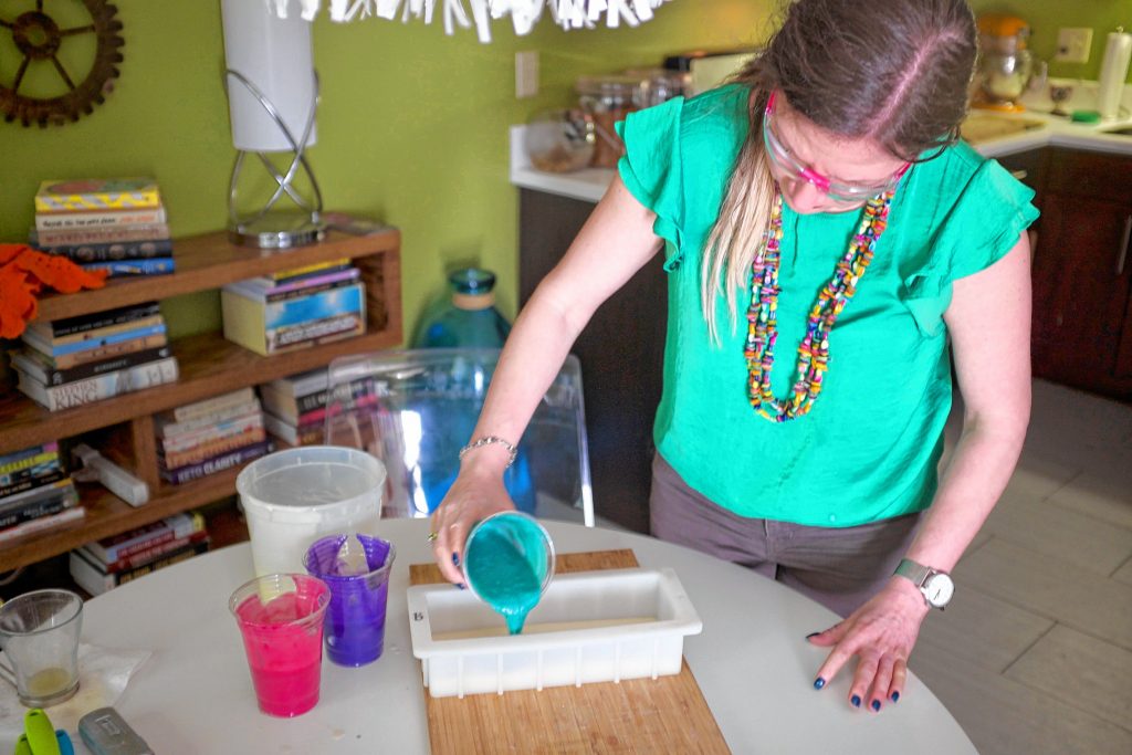 Bridget Overson pours differently colored soap into a mold in order to create swirled bars.