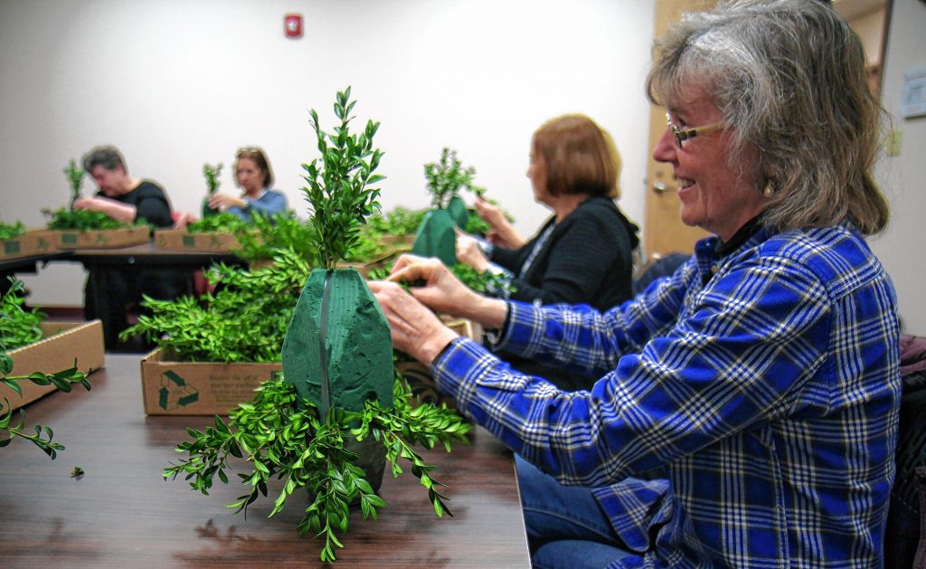 Linda Hodgdon of Concord works on assembling her Boxwood Christmas centerpiece at the Goodlife Center on North State Street in Concord on Monday, December 5, 2017. The water in the base allows the centerpiece to stay fresh through the holidays. GEOFF FORESTER