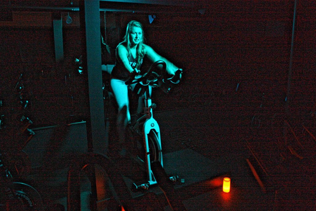 Meagan Ferns, owner of Strive Indoor Cycling, demonstrates how she leads her cycling classes at the studio. She likes to kill the main lights, leaving just a colored lamp on to illuminate her at the front of the class. JON BODELL / Insider staff