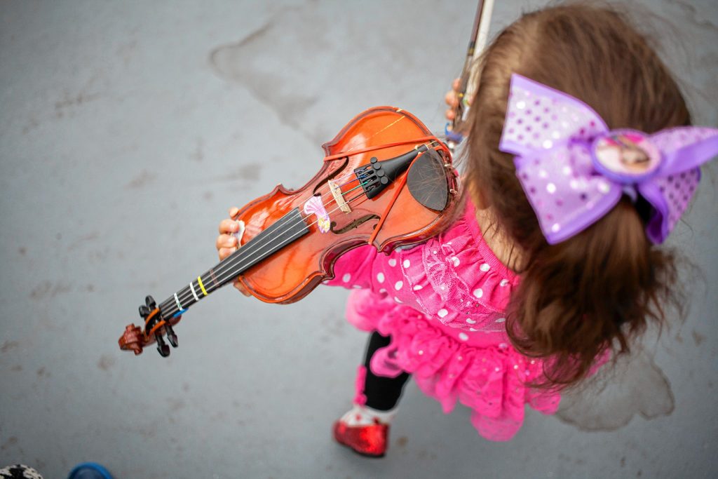 Two-year-old Rosalia Morris plays the fiddle with her sister at Concordâs Winter Farmers Market at Cole Gardens, April 2, 2016. (ELIZABETH FRANTZ / Monitor staff) Elizabeth Frantz
