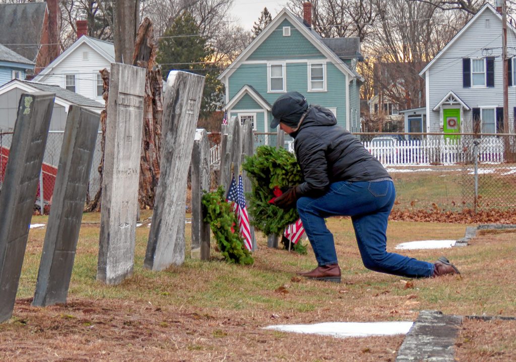 Pierce Brigade member Ginny Friburg lays a wreath on a veteran's grave in the Old North Cemetery in Concord on Friday. Caitlin Andrews
