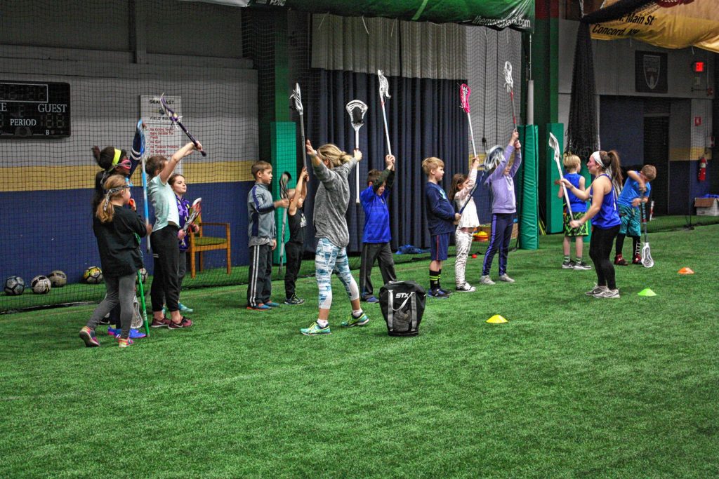 Emma Sisti (left), coach of the U10 boys' team, and Ella Doherty, a high school senior, lead a group of youth lacrosse players in a drill during a practice for Concord Crush youth lacrosse at the Seacoast United Concord Indoor Facility last week. JON BODELL / Insider staff