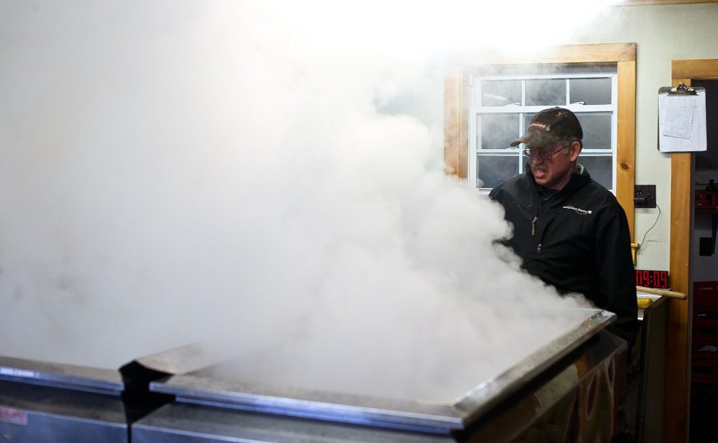 Larry Moore of Windswept Maple Farm in Loudon looks over the maple sryup evaporator as it heats up this week. The warm days have allowed the family farm to start processing syrup in February.  (GEOFF FORESTER / Monitor staff) 