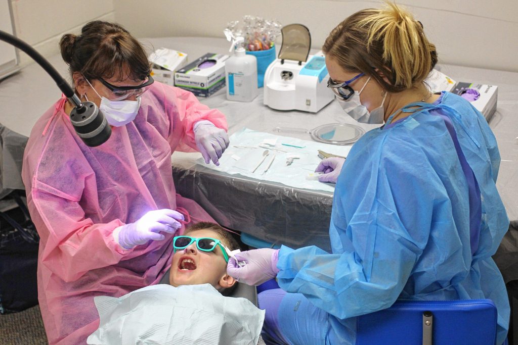 Certified Public Health Hygienist Mary Davis (left) and Dental Assistant Brittani Oldham (right) provide dental care to second-grader Brady Humphreys at Penacook Elementary School on Wednesday.