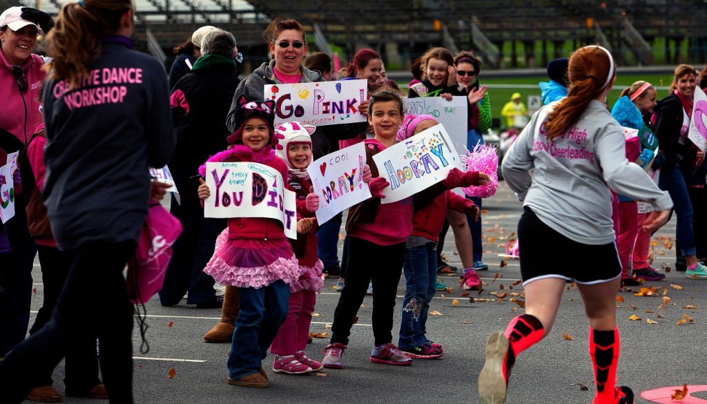 Avery Frazier, 7, left, Ally Moore, 7, center,  and Ramsey Drapeau, 7, along with Amanda Varney in back, hold up signs and greets runners at the Making Strides Against Breast Cancer Walk at the finish line at Memorial Field Sunday, October 19, 2014.  (GEOFF FORESTER / Monitor staff) Avery Frazier (left), 7, Ally Moore (center), 7, and Ramsey Drapeau, 7, along with Amanda Varney (in back), hold signs and greet runners at the Making Strides Against Breast Cancer walk at Memorial Field in Concord yesterday. 