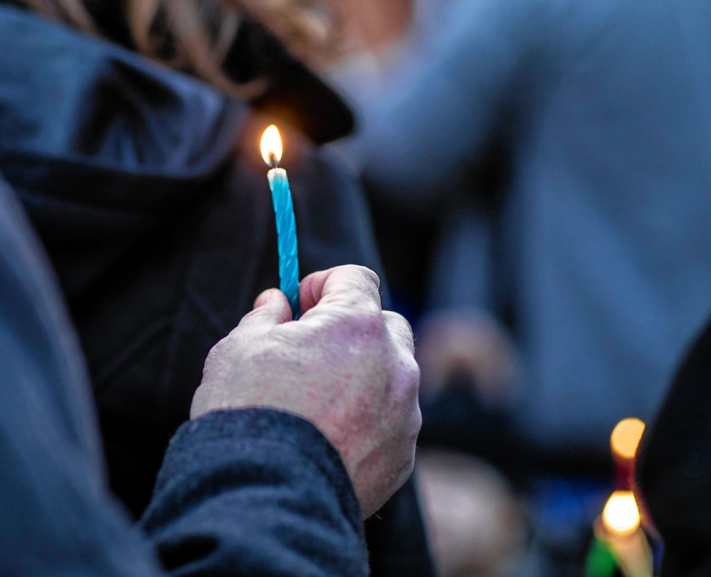 A lit candle is held after the Menorah Lighting at the State House on Sunday evening, December 22, 2019. Hanukkah is an eight-day Jewish festival with the first day known as Chanukah, Festival of Lights, and Feast of Dedication.  GEOFF FORESTER