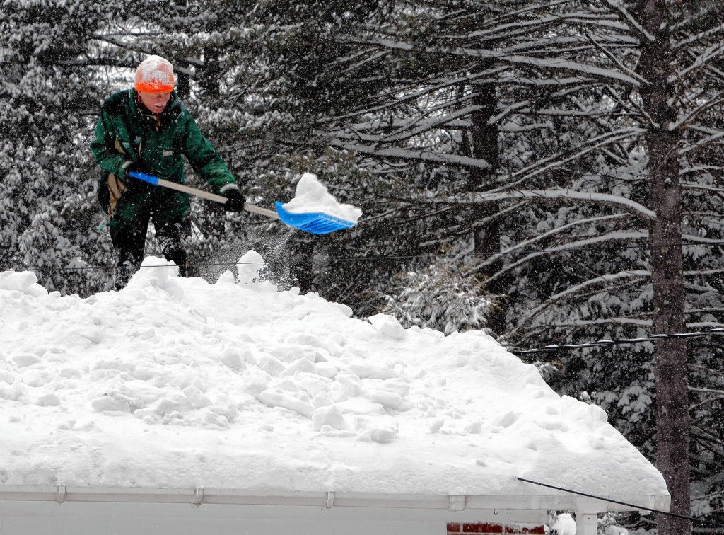 Bjorn Lange works to shovel off his roof as another snowstorm hits the area Monday, Feb. 9, 2015, in Concord, N.H. More light, fluffy snow was falling in much of New Hampshire on Monday, the latest in a series of storms piling it on this winter. (AP Photo/Jim Cole) Jim Cole