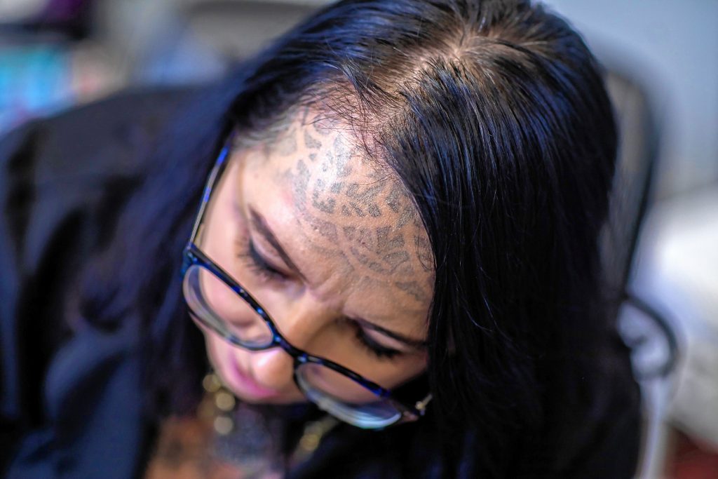 Angel Burnham concentrates on applying a tattoo at the Seven Horses Tattoo off of Warren Street in Concord on Friday, January 24, 2020. GEOFF FORESTER