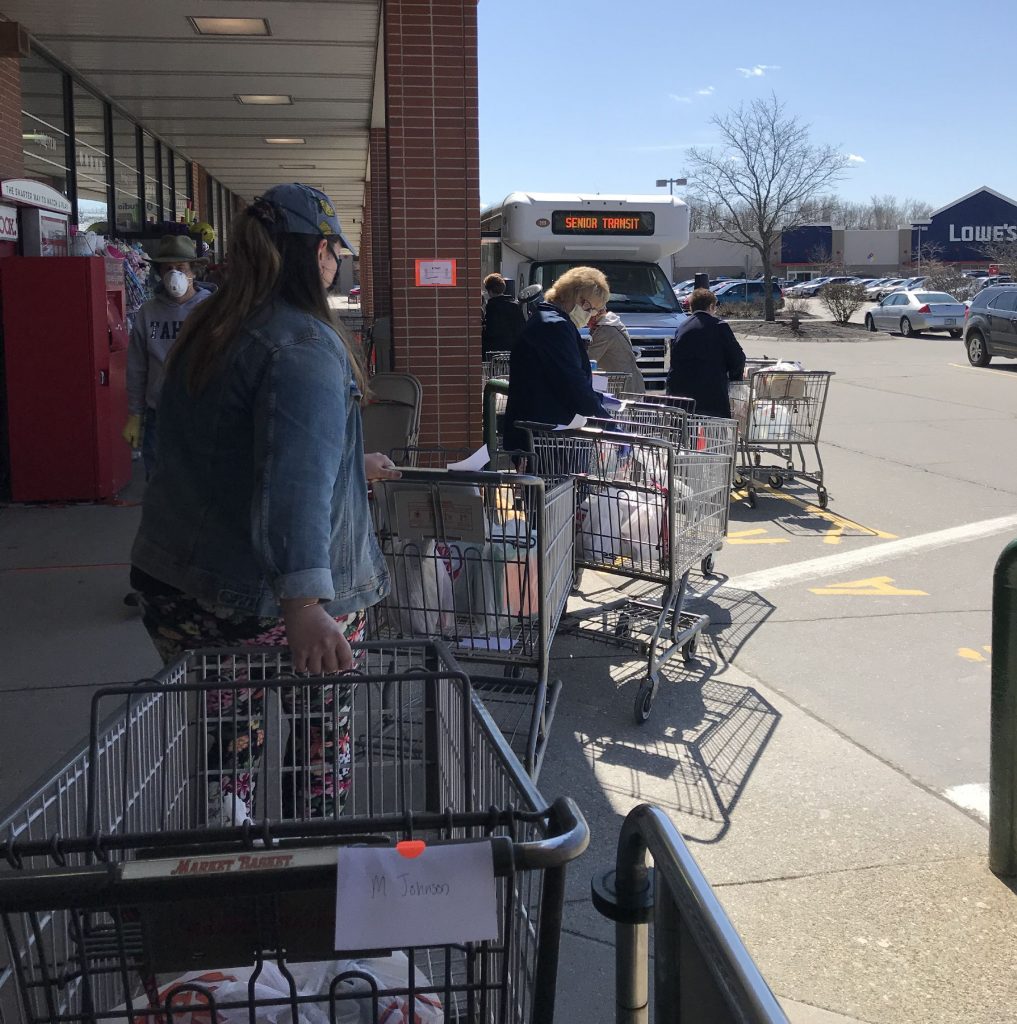 Volunteers wheel out carts of groceries to the waiting bus.