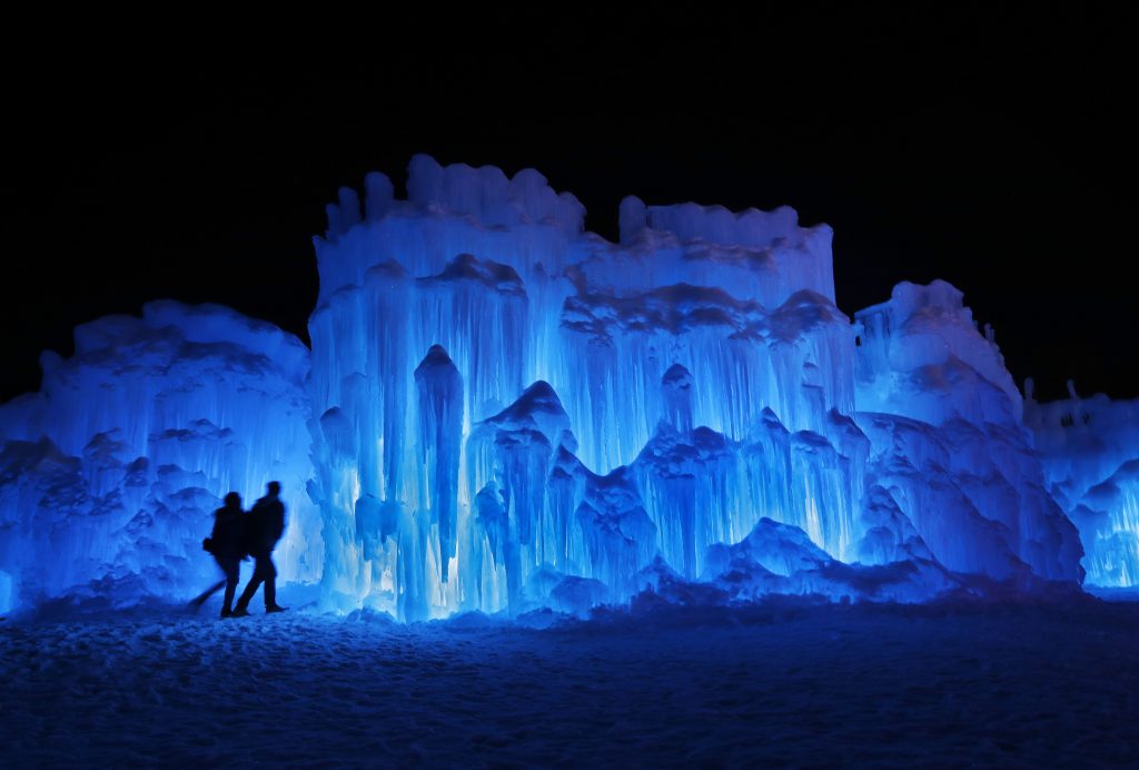 FILE – In this Saturday, Jan. 26, 2019 file photo, a couple heads toward an entrance to a cavern at Ice Castles in North Woodstock, N.H. A neighbor to the seasonal atraction alleges that melt water from the Ice Castles' property flooded her basement with over 15,000 gallons of water in April 2019. (AP Photo/Robert F. Bukaty, File) Robert F. Bukaty