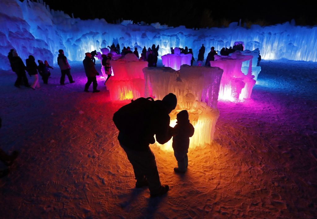 In this Saturday, Jan. 26, 2019 photo, Bruce McCafferty and his son, Dougie, pause while exploring the ice formations growing at Ice Castles in North Woodstock, N.H. (AP Photo/Robert F. Bukaty)  Robert F. Bukaty