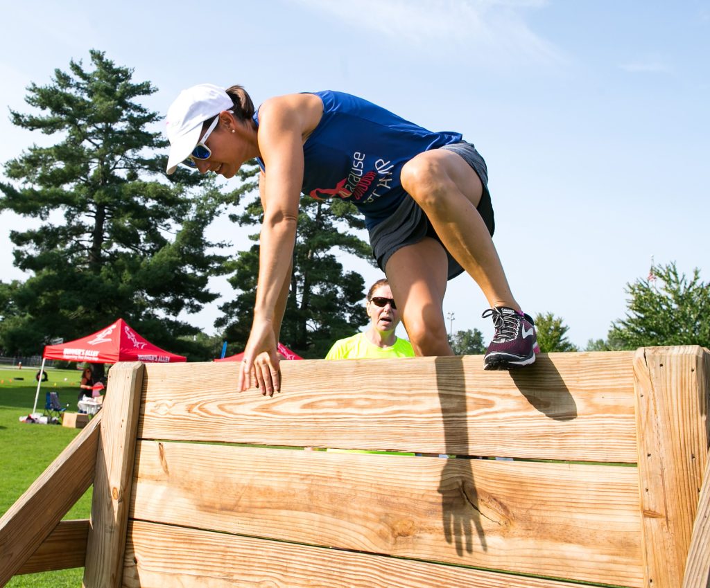 Renee Plodzik jumps over the obstacle wall at the boot camp she runs each Sunday through the summer at Memorial Field on August 19, 2018.  