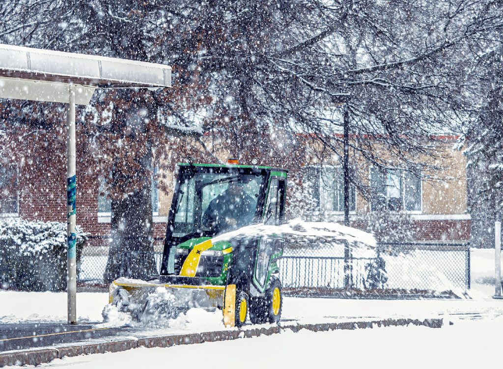 Travis Campbell cleans up the snow on the sidewalks at Rundlett Middle School during the snow storm on Friday, December 16, 2022. GEOFF FORESTER