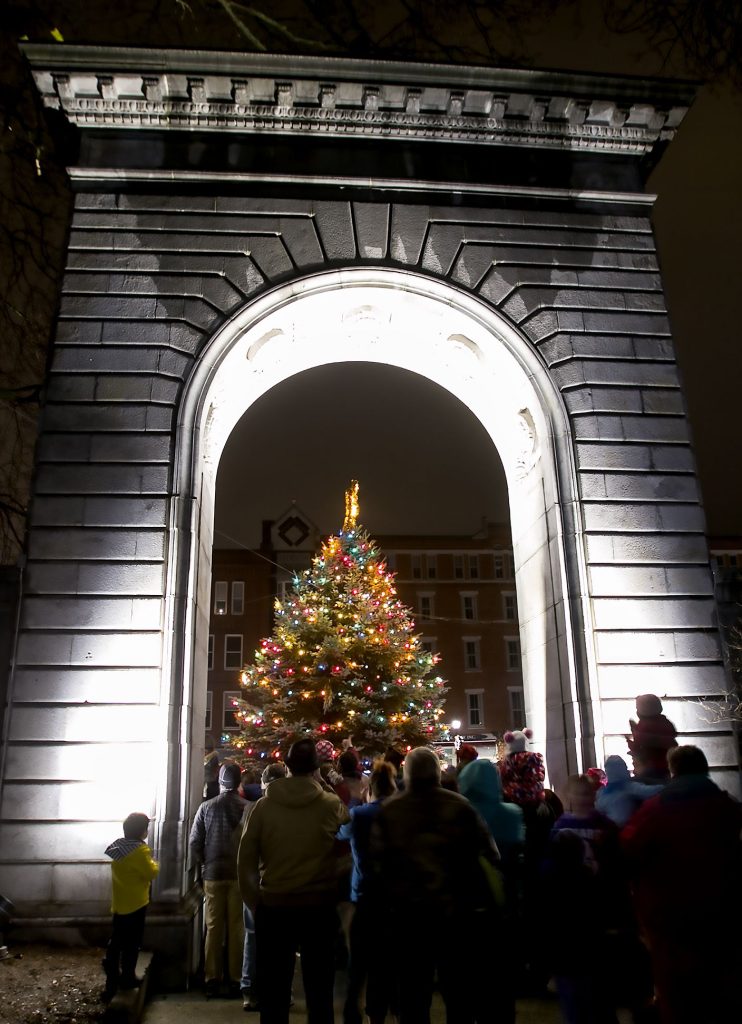 People watch from underneath the State House arch Friday night as the 30th annual Christmas tree lighting capped off a night of festivites. Santa Claus arrived via the Concord fire ladder truck and animal rides around the Park Street to Capitol Street and the evening finished with fireworks over Main Street. 